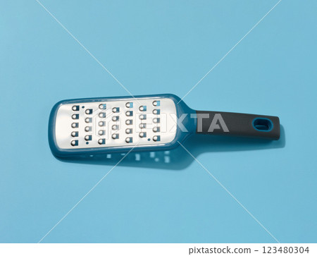 Metal vegetable grater on a blue background 123480304