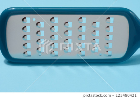 Metal vegetable grater on a blue background Metal vegetable grater on a blue background 123480421