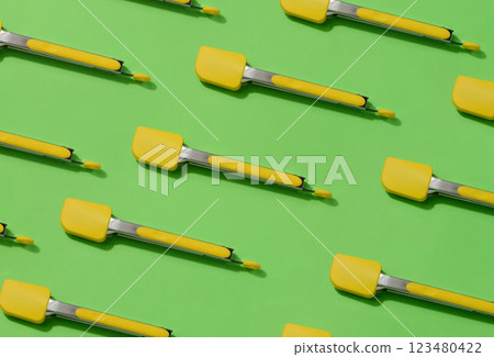 Yellow kitchen tongs with shadow on green background, pattern 123480422