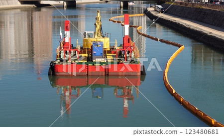 Heavy machinery and oil fences on a floating barge on the river 123480681