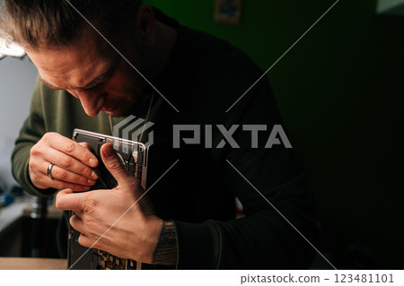 Computer technician examining and repairing components inside laptop during maintenance in dimly lit workshop, focusing on troubleshooting and problem-solving. Process electronic device repair. 123481101