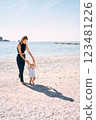 Little boy walks barefoot on a pebble beach holding his mother hands. High quality photo 123481226