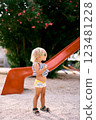 Little girl in sunglasses stands near a children slide. High quality photo 123481228