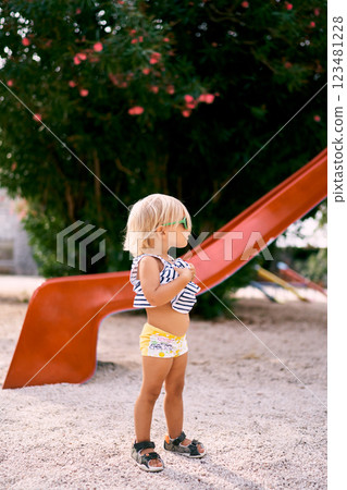 Little girl in sunglasses stands near a children slide. High quality photo Little girl in sunglasses stands near a children slide. High quality photo 123481228