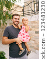 Smiling dad with a little girl in his arms near a stone fence. Portrait. High quality photo 123481230