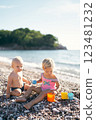 Little boy and girl with toy molds on a pebble beach. High quality photo 123481232