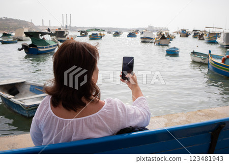 Woman traveler making photographs on a smartphone in fishing village Marsaxlokk on Malta 123481943