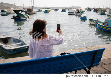 Woman traveler making photographs on a smartphone in fishing village Marsaxlokk on Malta 123481944