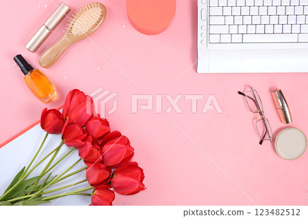 Work desk of a modern woman, home office. Notepad, tea, spring flowers and cosmetics on a light table. Minimal business concept, flat lay, place for text. 123482512