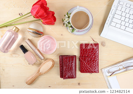 Work desk of a modern woman, home office. Notepad, tea, spring flowers and cosmetics on a light table. Minimal business concept, flat lay, place for text. 123482514