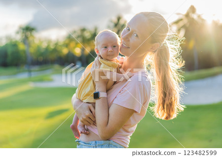 Young mother enjoying a peaceful walk in the park with her one-month-old baby. Motherhood, bonding, and outdoor family time concept 123482599