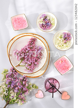 Fragrant pink salt, lilac water and lilac flowers. Spa and wellness composition, aromatherapy and skin care, lifestyle and organic cosmetics concept, salon invitation and advertisement, selective 123482842