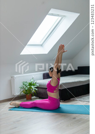 Cute sporty woman in pink leggings doing yoga exercises in a bright room Cute sporty woman in pink leggings doing yoga exercises in a bright room 123483231