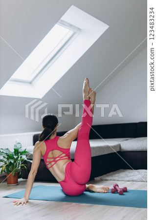 athletic girl in pink leggings and top crouches with dumbbells at home.Sport,yoga,healthy lifestyle. athletic girl in pink leggings and top crouches with dumbbells at home.Sport,yoga,healthy lifestyle. 123483234