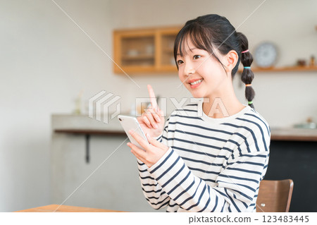 小學和國中女生在家中客廳和餐廳使用智慧型手機 小學和國中女生在家中客廳和餐廳使用智慧型手機 123483445