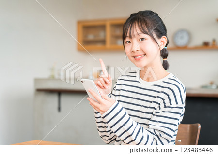 Elementary and junior high school girls using smartphones in the living room and dining room at home Elementary and junior high school girls using smartphones in the living room and dining room at home 123483446