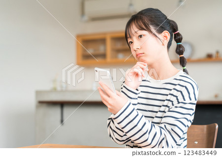 小學和國中女生在家中客廳和餐廳使用智慧型手機 小學和國中女生在家中客廳和餐廳使用智慧型手機 123483449