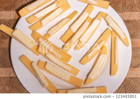 A white plate with several pieces of cheese and small pats of butter on top A white plate with several pieces of cheese and small pats of butter on top 123483801