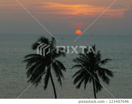 Bright orange sun setting over the ocean with tropical palms creating a serene island view. Ko Pha Ngan, Thailand. 123487046