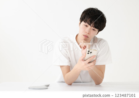 A young man thinking while looking at his smartphone 123487101