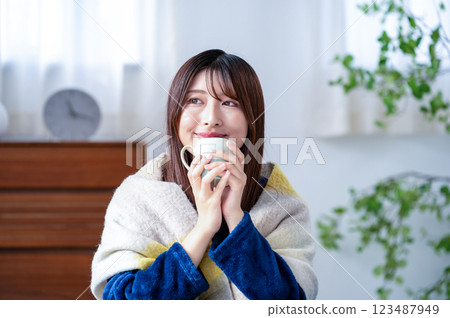 冬季客廳裡拿著杯子的年輕女子 123487949