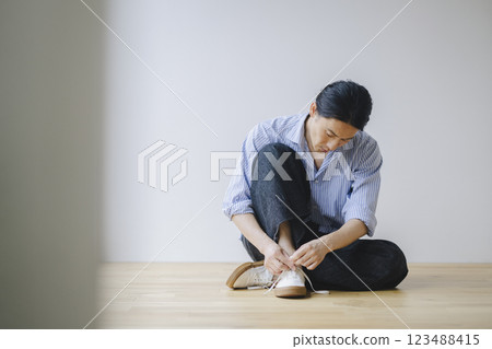 一名 40 多歲的男子正在繫上運動鞋鞋帶 一名 40 多歲的男子正在繫上運動鞋鞋帶 123488415