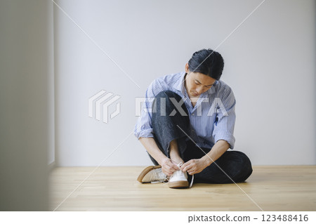 一名 40 多歲的男子正在繫上運動鞋鞋帶 123488416