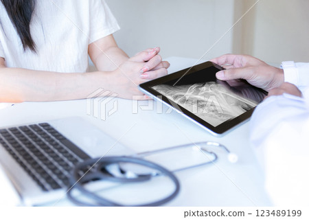 The doctor examines the patient and looks at an X-ray of the shoulder. The doctor examines the patient and looks at an X-ray of the shoulder. 123489199