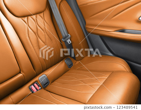 Back passenger black seats in modern luxury car. Brown perforated leather with white stitching. Car details. Leather comfortable seats. Car interior details 123489541