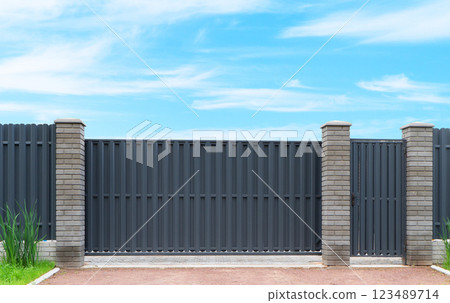 Modern aluminium sliding gate. Gate portal of suburb door house. Modern steel fence around the house over blue sky. Design and architecture of a modern house. 123489714