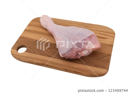 Raw turkey drumstick on wooden board isolated on white background. Turkey leg isolated. Raw turkey drumstick on wooden board isolated on white background. Turkey leg isolated. 123489744