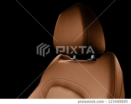 Car brown leather interior. Part of brown leather car seat details with white stitching. Interior of prestige car. Perforated leather seats isolated on black. Perforated leather. 123489895