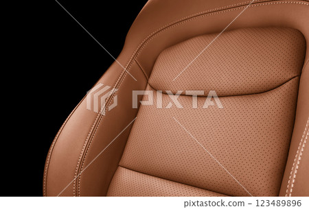 Car brown leather interior. Part of brown leather car seat details with white stitching. Interior of prestige car. Perforated leather seats isolated on black. Perforated leather. Car brown leather interior. Part of brown leather car seat details with white stitching. Interior of prestige car. Perforated leather seats isolated on black. Perforated leather. 123489896