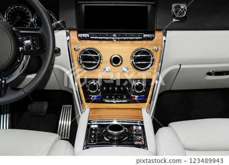 Modern luxury car white leather interior with natural wood panel. Part of leather car seat details with stitching. Interior of prestige modern car. White perforated leather. Car detailing. Car inside 123489943