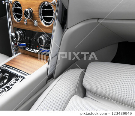 Modern luxury car white leather interior with natural wood panel. Part of leather car seat details with stitching. Interior of prestige modern car. White perforated leather. Car inside Modern luxury car white leather interior with natural wood panel. Part of leather car seat details with stitching. Interior of prestige modern car. White perforated leather. Car inside 123489949
