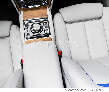 Modern luxury car white leather interior with natural wood panel. Part of leather car seat details with stitching. Interior of prestige modern car. White perforated leather. Car inside 123489956