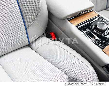 Modern luxury car white leather interior with natural wood panel. Part of leather car seat details with stitching. Interior of prestige modern car. White perforated leather. Car inside Modern luxury car white leather interior with natural wood panel. Part of leather car seat details with stitching. Interior of prestige modern car. White perforated leather. Car inside 123489958