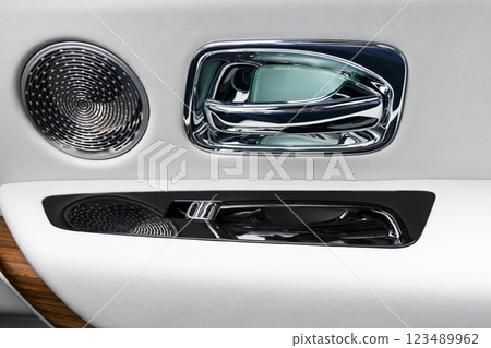 Door handle with power window control buttons of a luxury passenger car. White perforated leather interior with stitching and wood panel. Modern car interior details.. Car inside Door handle with power window control buttons of a luxury passenger car. White perforated leather interior with stitching and wood panel. Modern car interior details.. Car inside 123489962