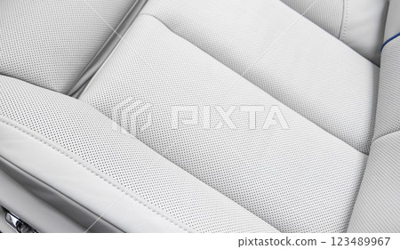 White leather interior of the luxury modern car. Perforated white leather comfortable seats with stitching. Modern car interior details. 123489967