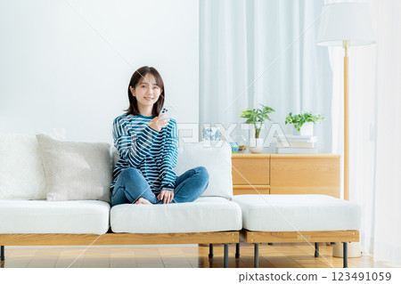 在房間裡操作智慧型手機的年輕女子 在房間裡操作智慧型手機的年輕女子 123491059