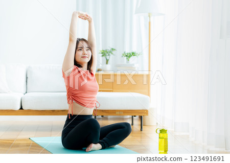 年輕女子在客廳裡做瑜伽 年輕女子在客廳裡做瑜伽 123491691