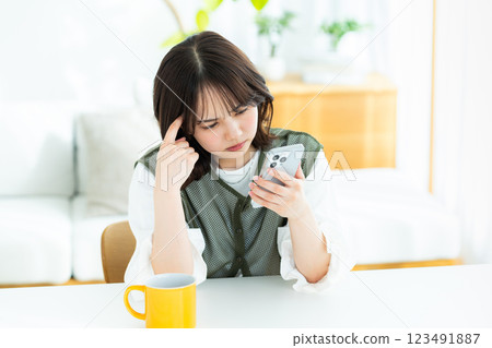 A young woman operating a smartphone in a room 123491887