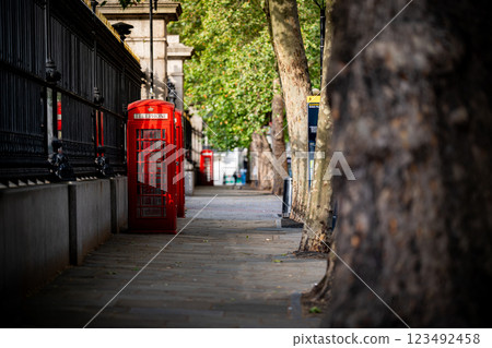 A red telephone booth on a peaceful London sidewalk, framed by trees, brings together the charm of the city past and its natural beauty. A red telephone booth on a peaceful London sidewalk, framed by trees, brings together the charm of the city past and its natural beauty. 123492458