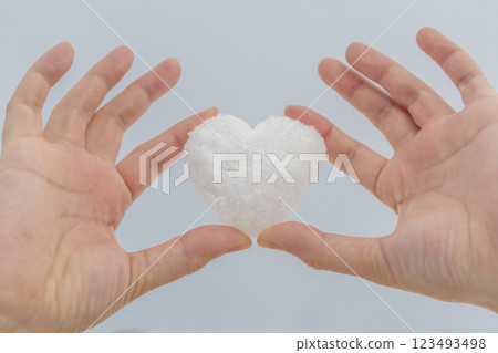 Woman's hand holding heart shaped snowflakes 123493498