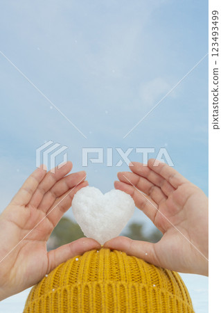 Woman holding heart-shaped snowflakes on her head 123493499