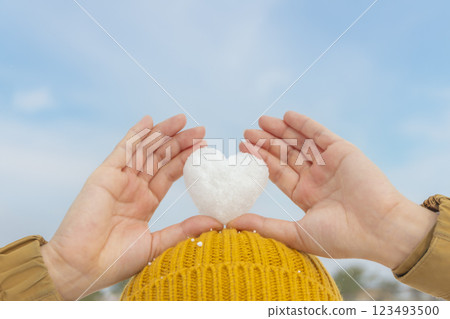 Woman holding heart-shaped snowflakes on her head 123493500