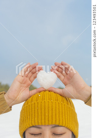 Woman holding heart-shaped snowflakes on her head 123493501