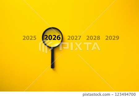 Magnifying glass focusing on year 2026 among other years on yellow background Magnifying glass focusing on year 2026 among other years on yellow background 123494700