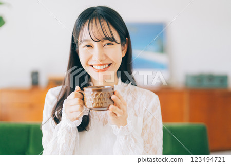 A woman sitting on a sofa and drinking coffee A woman sitting on a sofa and drinking coffee 123494721