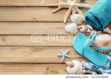 Different seashells with towels and flip flops on brown wooden table Different seashells with towels and flip flops on brown wooden table 123494898